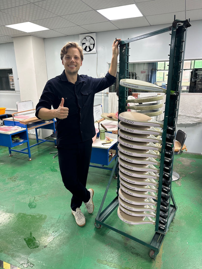 OTARO-Gründer in der Padelschläger-Produktion vor einem Gestell mit frisch lackierten PULSE-Schlägern